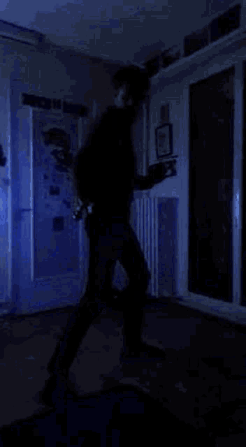 a man is standing in a dark room with a blue light coming out of his hands .