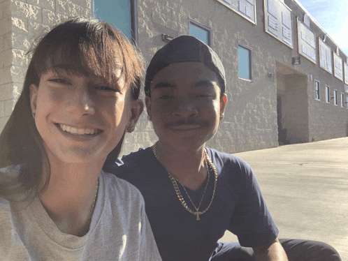 a man and woman are posing for a picture in front of a building