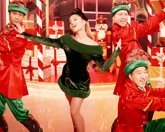 a woman in a green dress is dancing in front of a nutcracker and presents