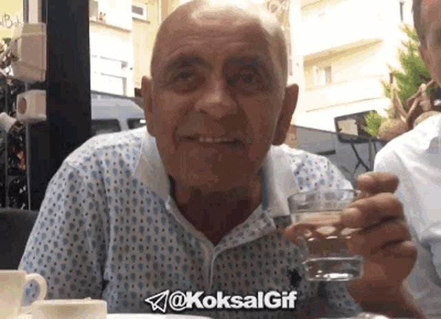 an older man is holding a glass of water with the hashtag @koksalgif on the bottom right