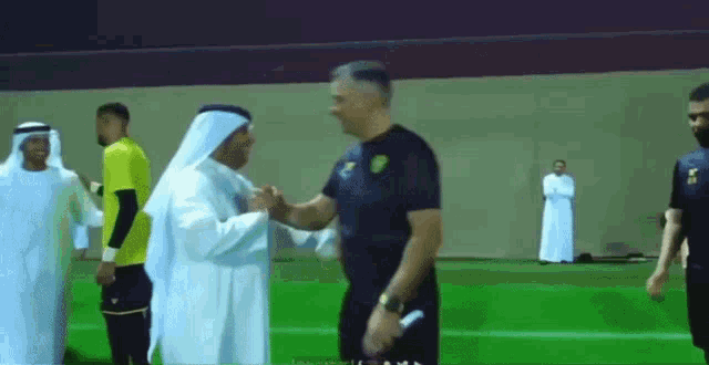 two men are shaking hands on a soccer field