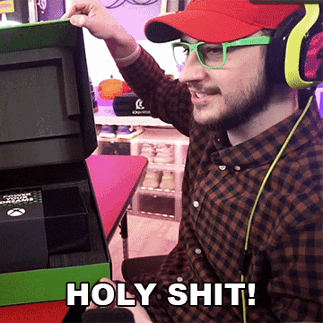 a man wearing headphones and glasses is holding a box that says holy shit on it
