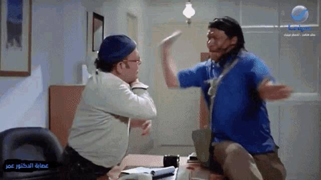 a man in a blue shirt is fighting another man in a white shirt in a scene from a movie