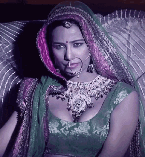 a woman with a nose ring is wearing a green top and a pink veil