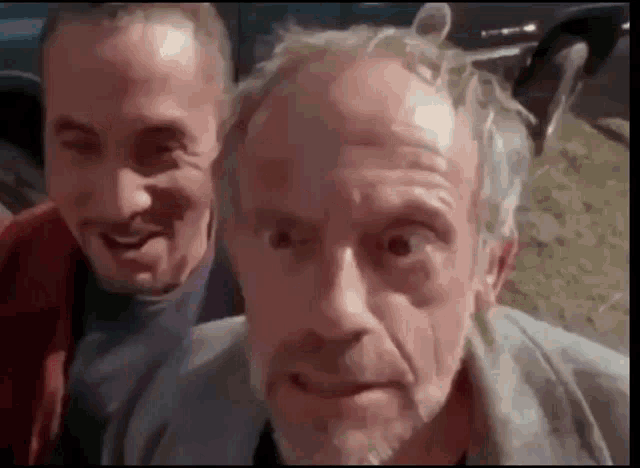 a couple of men are standing next to each other and making funny faces .
