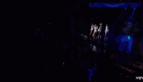 a group of women are singing and dancing on a stage with the word vev in the corner