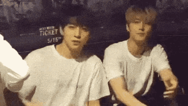 two young men sitting next to each other in front of a sign that says ticket