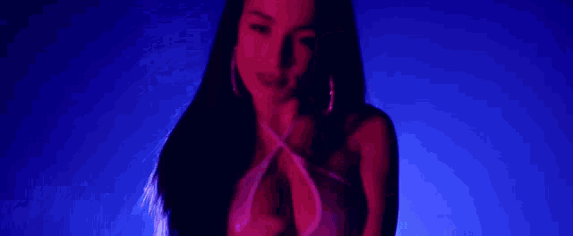 a woman in a white top is dancing in a dark room with purple lights .