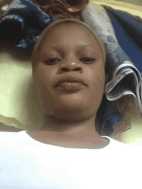a woman laying on a bed with a blue blanket on top of her head