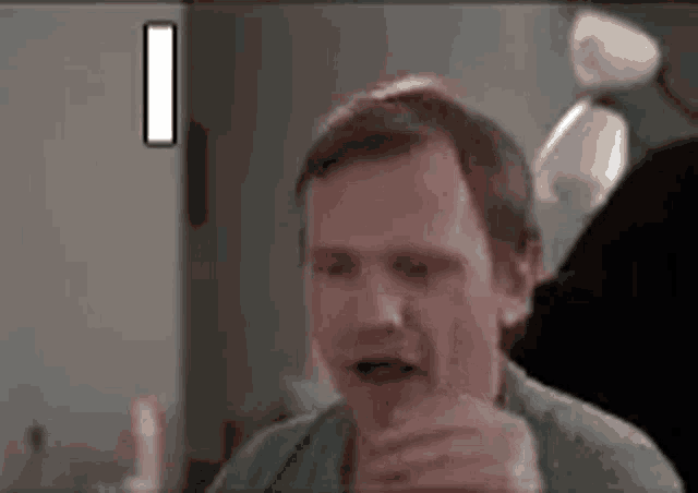 a man is brushing his teeth in a bathroom while looking at a mirror .
