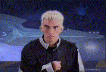 a man with blonde hair is standing in front of a blue car .