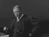 a man in a suit and tie is pointing to something