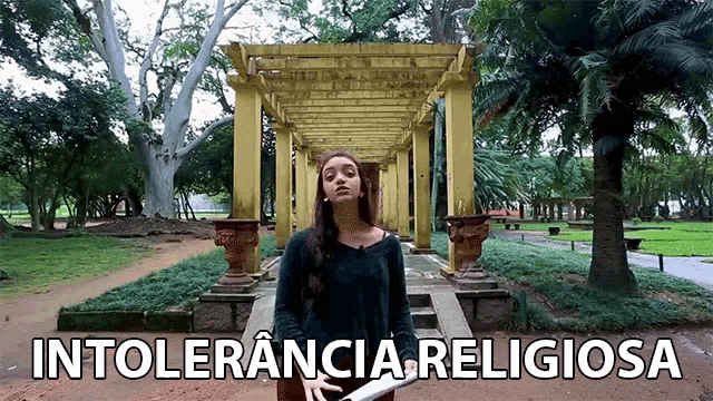 a woman stands in a park with the words intolerancia religiosa written on the bottom