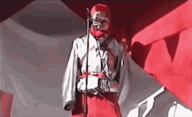 a person wearing a red mask is standing in front of a microphone