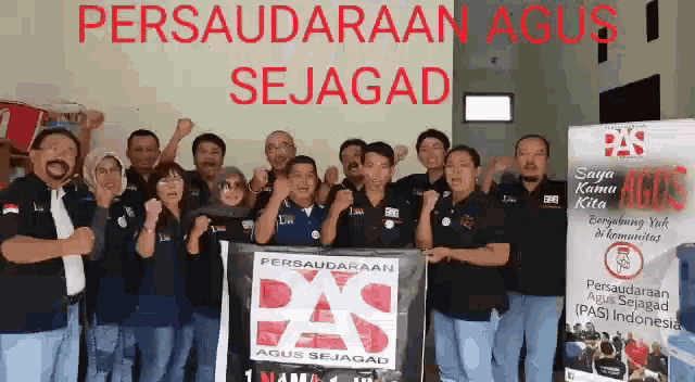 a group of people standing in front of a sign that says ' persaudaraan agus sejagad '