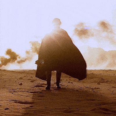 a person in a black cape is standing in the desert