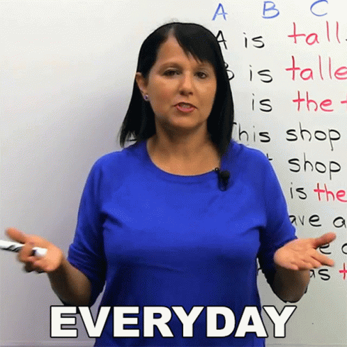 a woman in a blue shirt is standing in front of a white board with the word everyday written on it