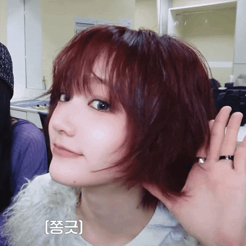 a woman with red hair has a ring on her finger and a foreign language written on her face