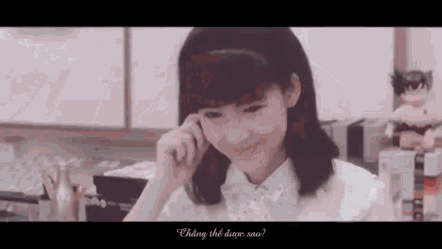 a young girl is sitting at a table talking on a cell phone and smiling .