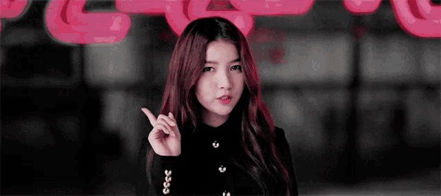 a young woman with red hair is pointing up with her finger .