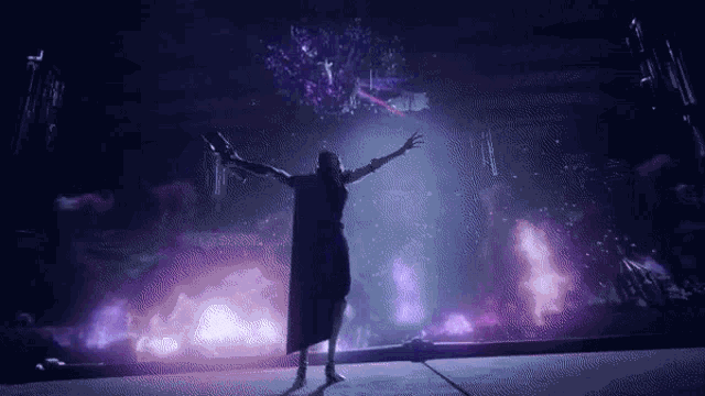 a woman in a cape is standing in front of a fireworks display .