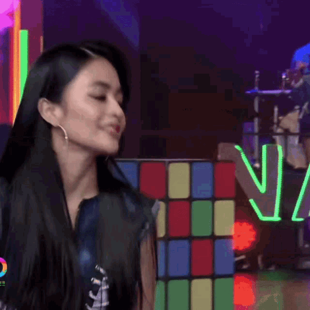 a woman is smiling in front of a neon sign that says n1