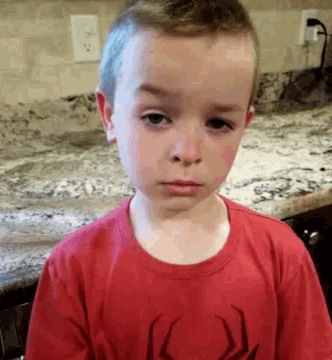 a young boy wearing a red spider man shirt