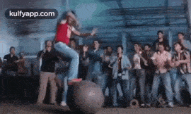 a woman is standing on top of a large ball in front of a crowd .