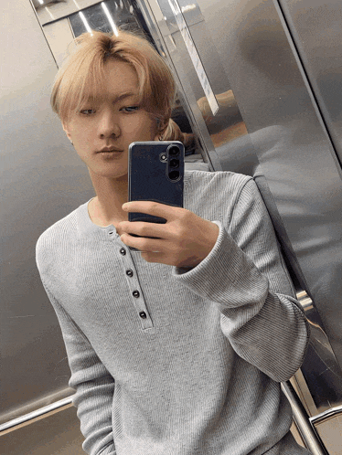 a young man taking a selfie with his phone in an elevator