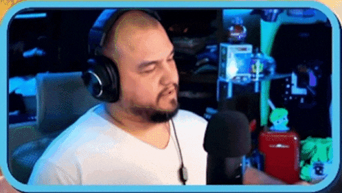 a man wearing headphones is standing in front of a microphone in a room .