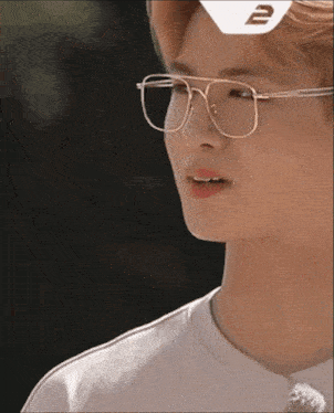 a close up of a person wearing glasses and a white shirt with a 2 on it