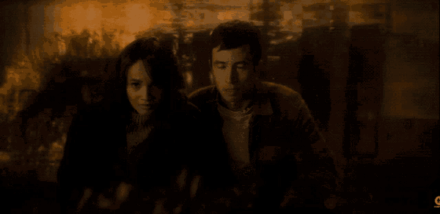 a man and a woman are standing next to each other in a dark room with the letter c on the bottom