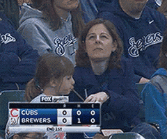 a group of people watching a baseball game with a scoreboard that says cubs brewers on it