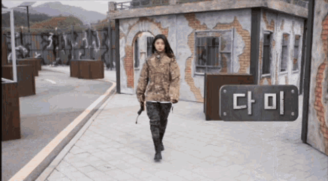 a woman walking in front of a building with a sign that says " 다미 "