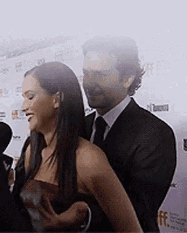 a man in a suit and tie is putting his arm around a woman in a red dress