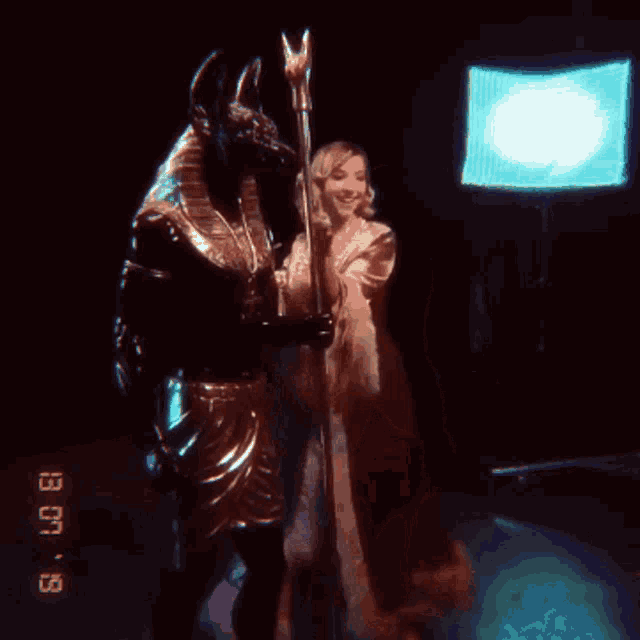 a woman in a dress is standing next to a statue of anubis with the date of 9/8