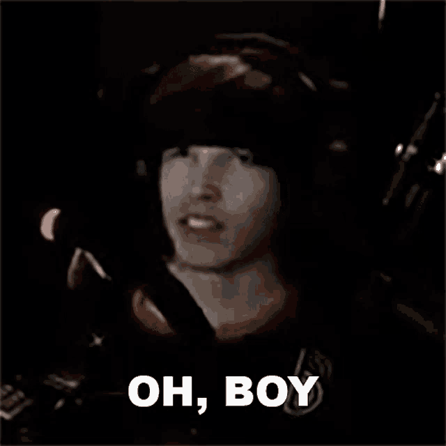 a man wearing headphones is talking into a microphone in a dark room and saying `` oh , boy '' .
