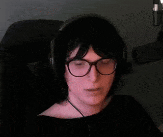 a person wearing glasses and headphones is sitting in a chair .
