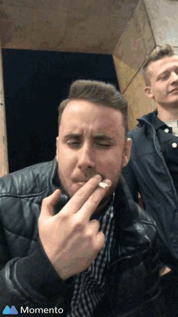 a man smoking a cigarette next to another man with the word momento on the bottom right