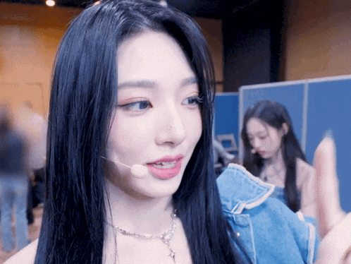 a woman with long black hair wearing a microphone