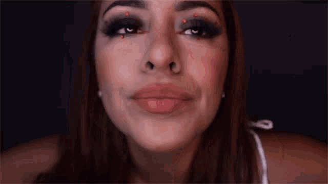 a close up of a woman 's face with red rhinestones on her eyes and nose .