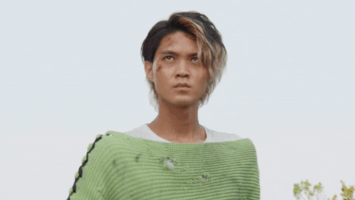 a man in a green sweater is holding a green object in his hands .