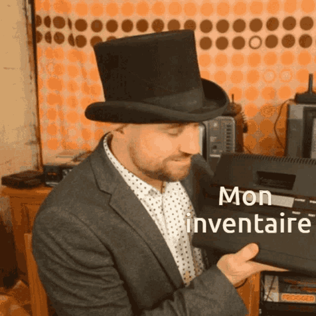 a man wearing a top hat and a suit is holding a black box that says mon inventaire