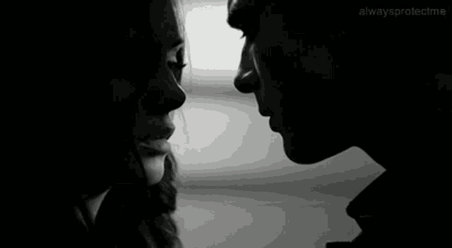 a man and a woman are looking into each other 's eyes in a black and white photo .