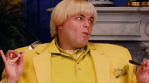 a man in a yellow suit is eating with a fork