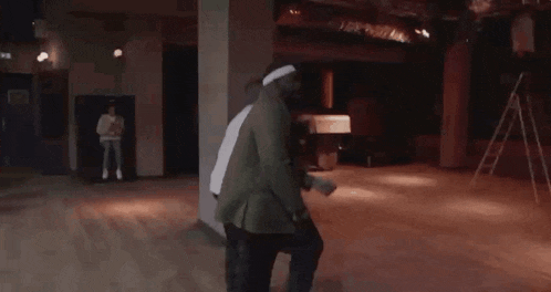 a man in a green jacket is dancing with another man in a white shirt .