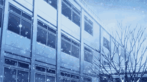 it is snowing outside of a school building with trees in the foreground .