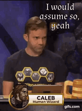 a man in a caleb human wizard shirt sits at a table