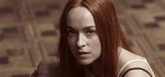 a woman with red hair is looking at the camera with a serious look on her face