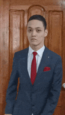 a man in a suit and tie stands in front of a door